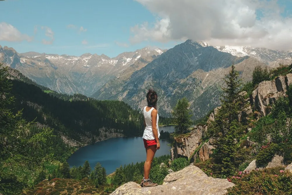 mujer de pie sobre una roca en la cima de una montaña