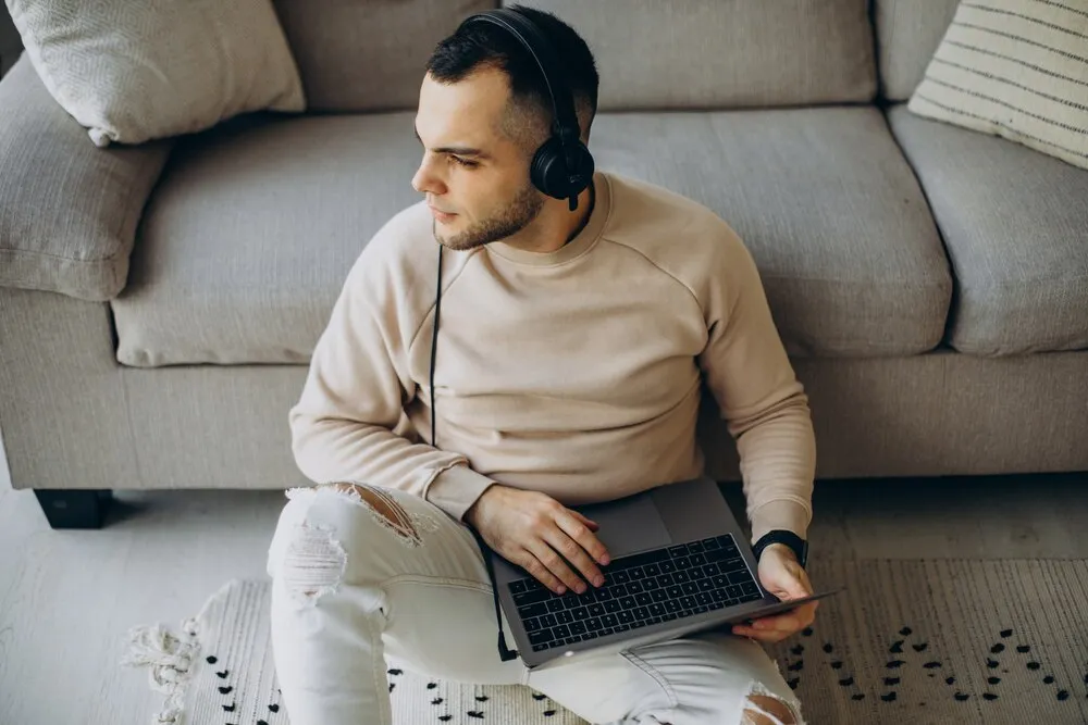 Joven con auriculares usando el ordenador en casa