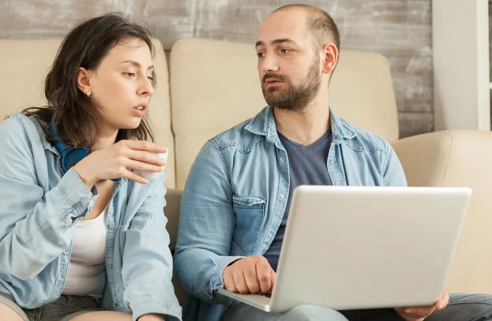 pareja relajándose en el salón tomando café y navegando por internet