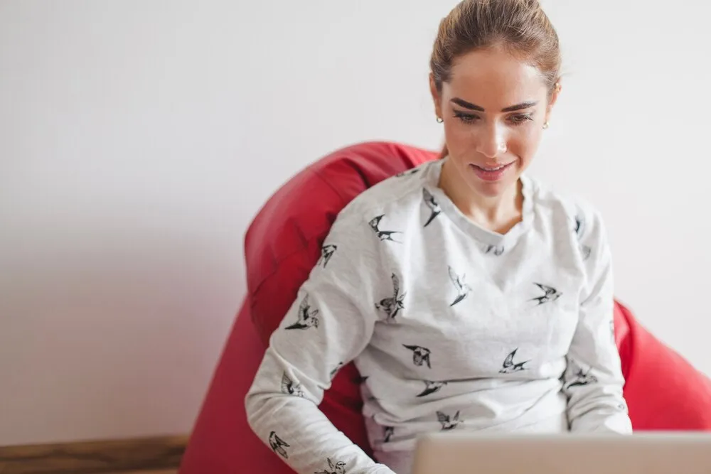 mujer en un sillón mirando un portátil