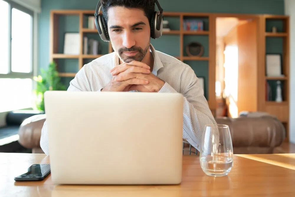 Retrato de un hombre joven en una videollamada de trabajo con un portátil desde casa. Concepto de teletrabajo. Estilo de vida de la nueva normalidad.