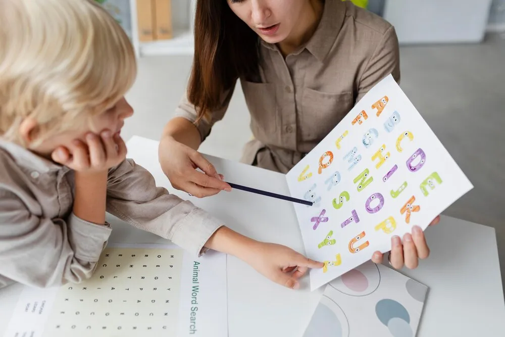 mujer realizando logopedia con un niño pequeño en su clínica