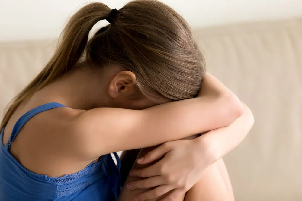 mujer sola abrazándose las rodillas y llorando