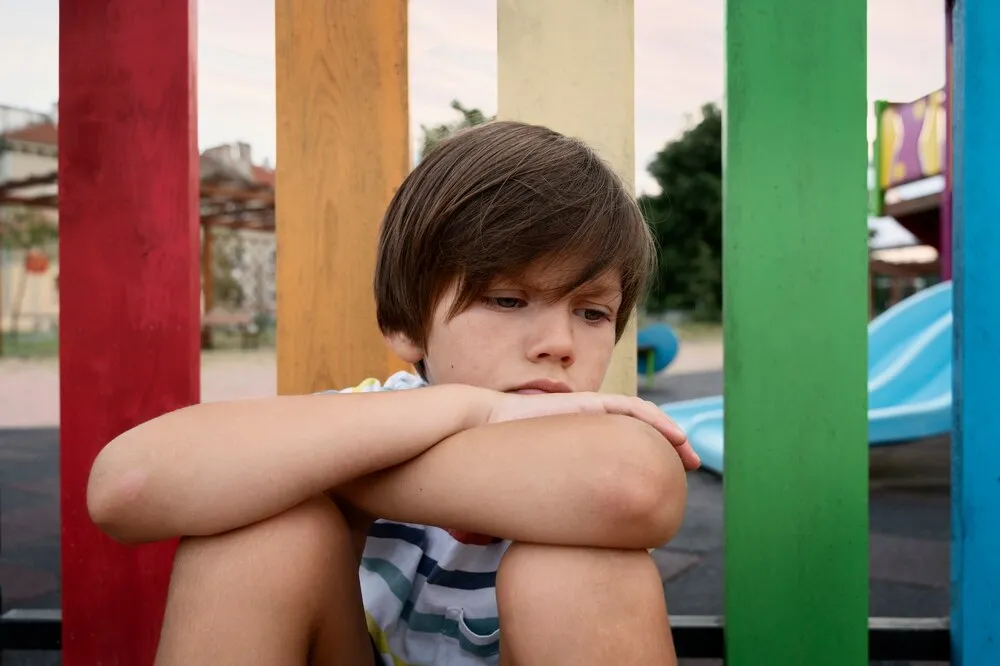 plano medio niño triste sentado al aire libre