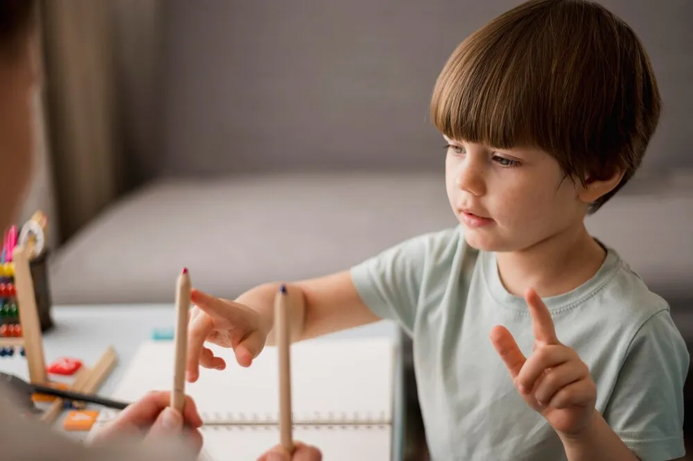 vista lateral de un niño aprendiendo a contar en casa con lápices