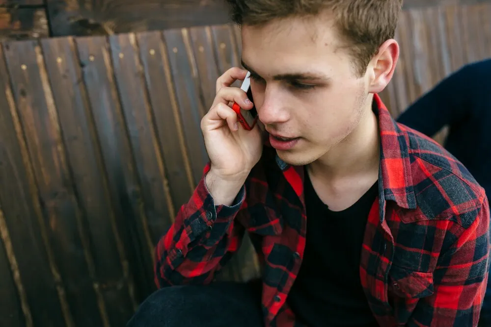 primer plano de un adolescente guapo hablando por teléfono