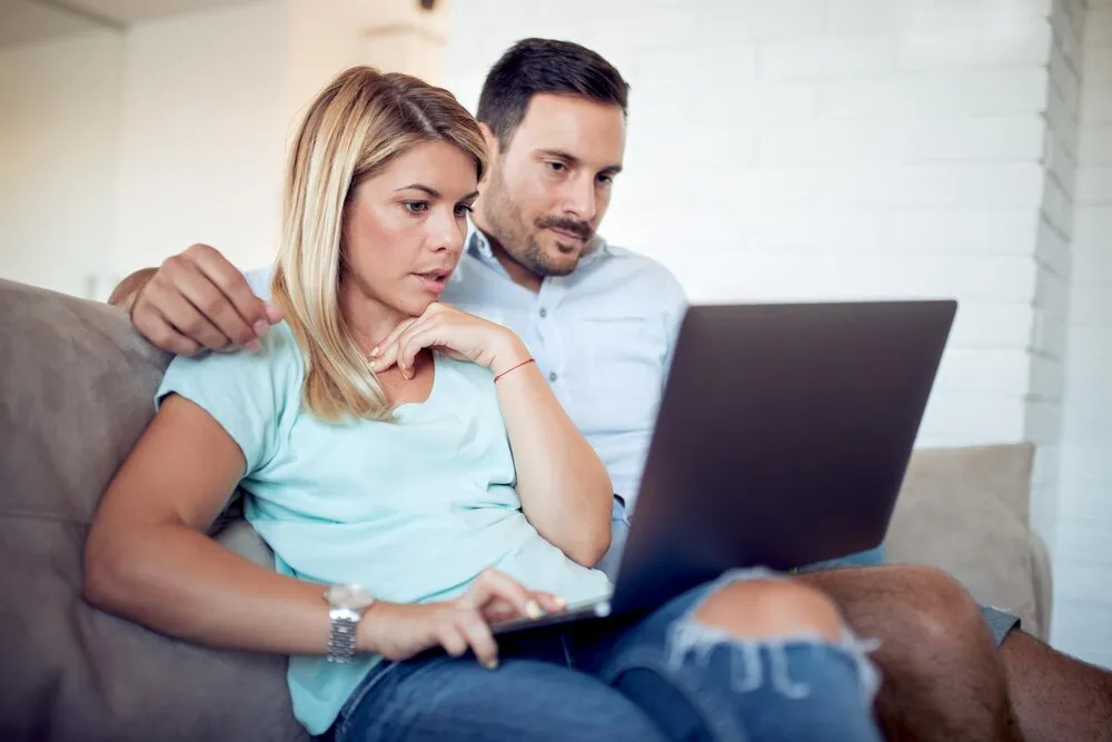Pareja relajándose en el sofá y usando un ordenador portátil