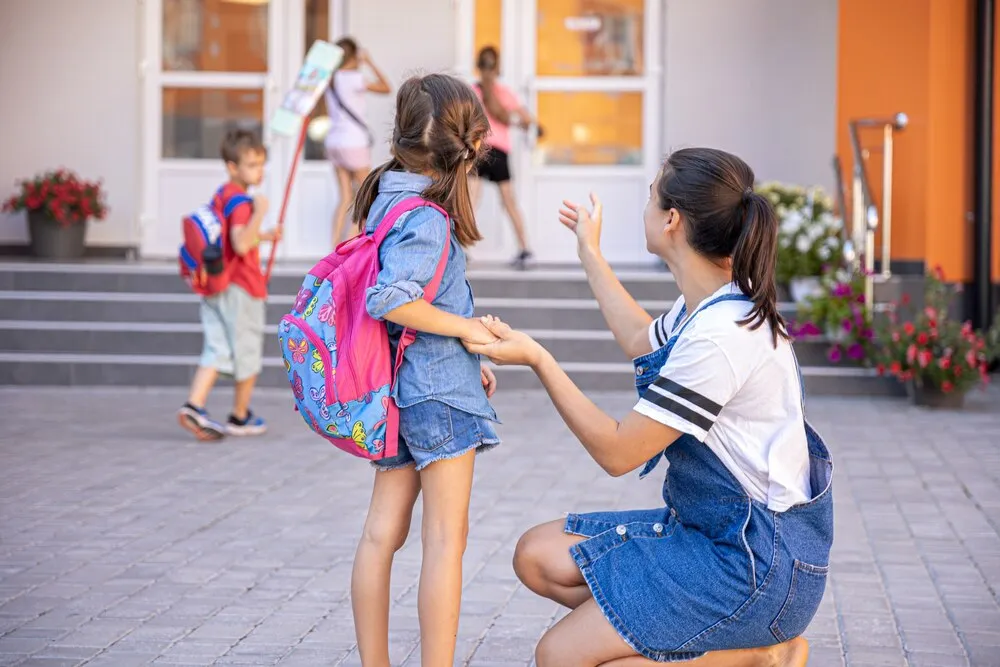 una madre acompaña a la estudiante a la escuela, niña feliz con una madre cariñosa, vuelta al colegio.