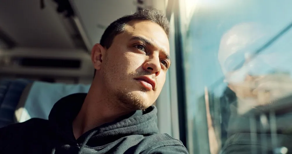 hombre joven pensativo y triste en un tren con problemas de salud mental o soledad en un viaje o trayecto, depresión, afligido y hombre canadiense en transporte público por vacaciones o días festivos