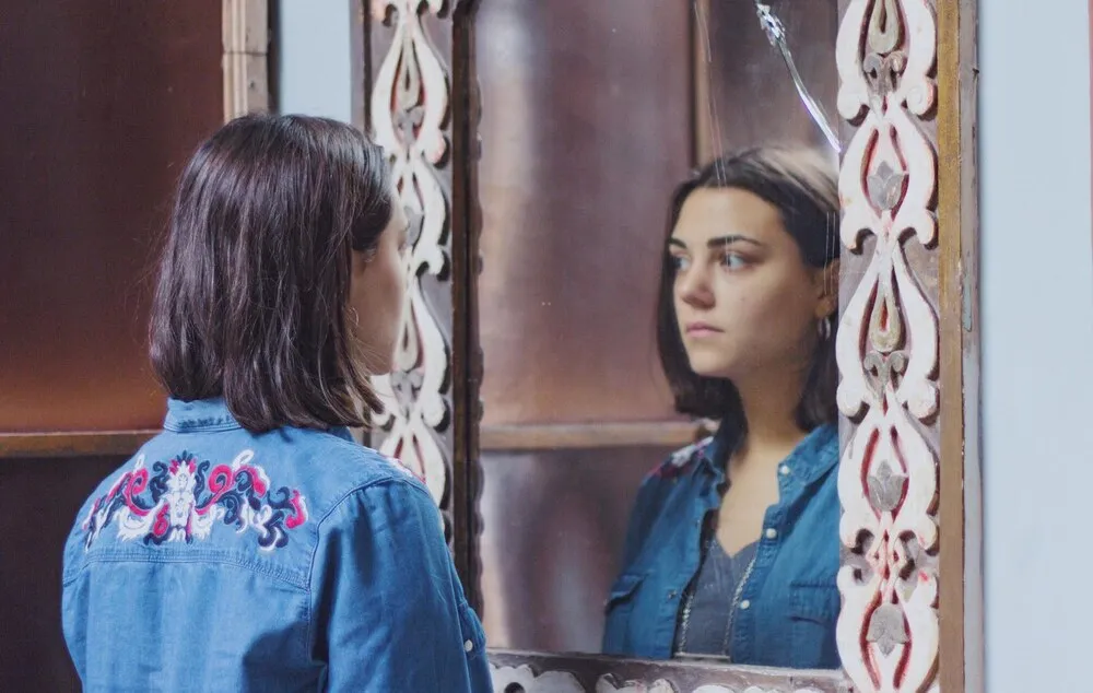 mujer joven reflejada en el espejo