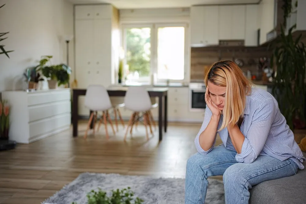 mujer triste sentada en el sofá en casa con problemas de salud mental