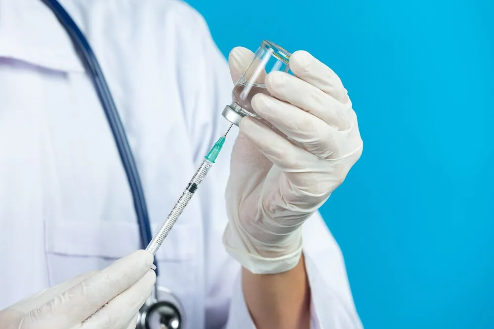 Primer plano de las manos de un médico sosteniendo una jeringuilla hipodérmica.