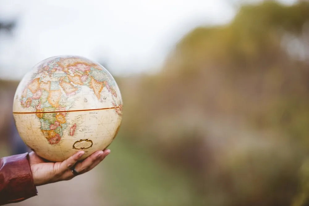 primer plano de un hombre sosteniendo un globo terráqueo con un fondo desenfocado