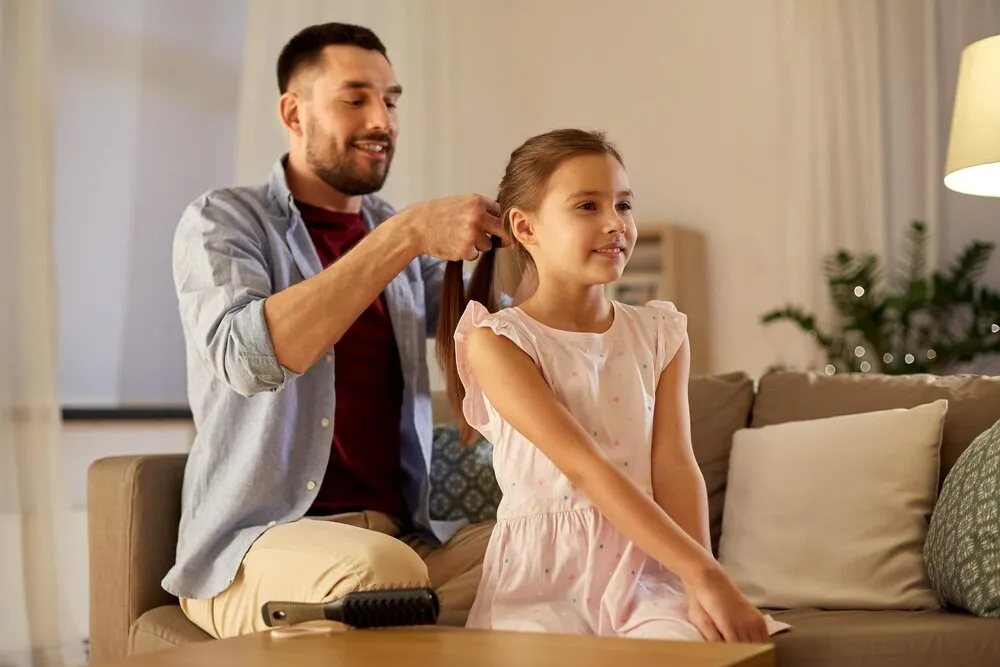 Padre trenzando el pelo de su hija en casa